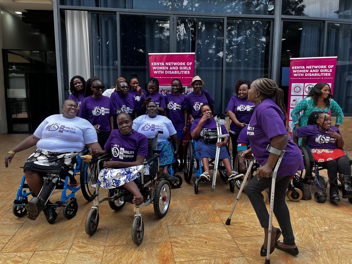 Network members in matching purple t-shirts, several using wheelchairs and crutches, gathered outdoors
